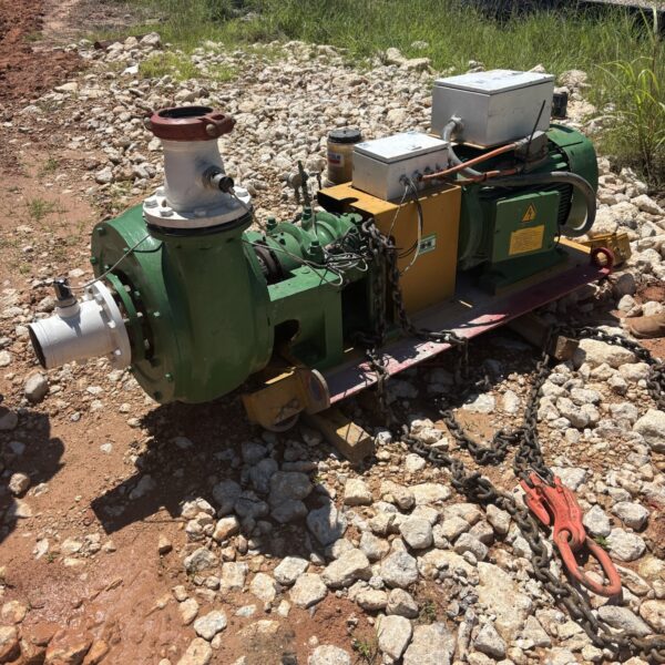 81A97E65-A5AD-4EC1-9B70-904A01742301 - Big River Trenchless & GeoServices Industrial pump setup on a rocky construction site with hoses and chains attached; orange safety fencing in the background.