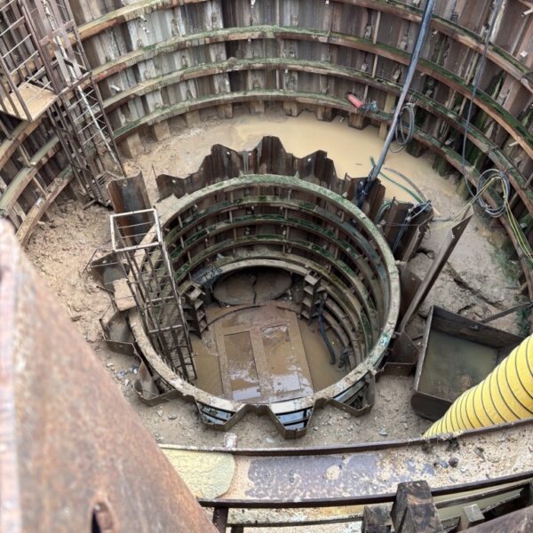 FWSD 23_20260528 8 - Big River Trenchless & GeoServices Deep circular excavation with multiple concentric steel sheet piles, ladders, and muddy water at the bottom of a construction shaft