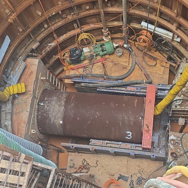 IMG_2026_07_02_18_02_27_217 - Big River Trenchless & GeoServices Construction shaft with wooden/steel rings, a green pump/motor, and scattered orange cables inside a circular excavation area.