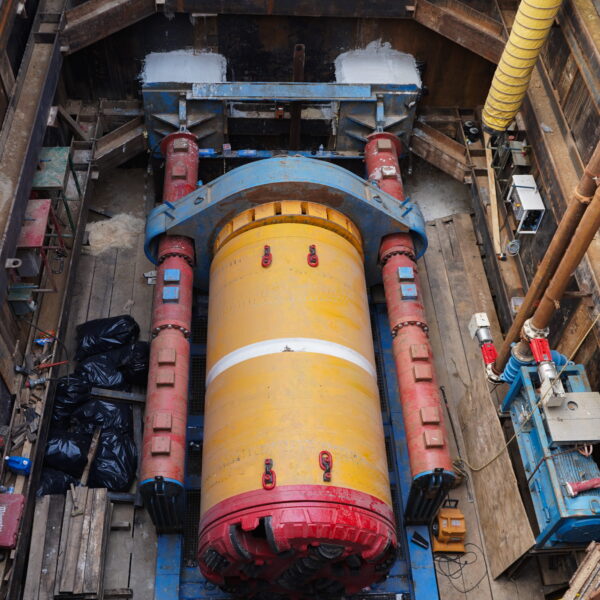 WHCRWA-Contract-64-Img2 - Big River Trenchless & GeoServices Industrial trench with a large yellow cylindrical component and red piping, supported by a blue frame and wooden shoring.